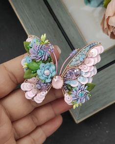 a person is holding a small butterfly brooch in their hand