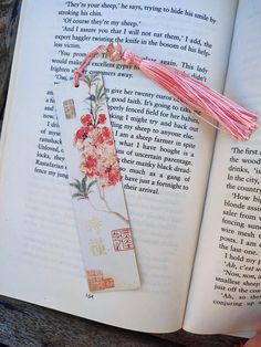 an open book with flowers on it and a tassel hanging from the front cover