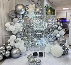 silver and white balloons are on display in front of a mirror wall with the words happy birthday