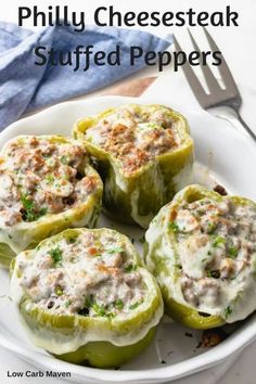 several stuffed peppers on a white plate with a fork and napkin next to it,