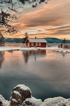 a red house sitting on top of a lake covered in snow