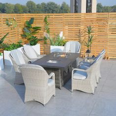 an outdoor dining table and chairs on a patio with wooden fence in the back ground