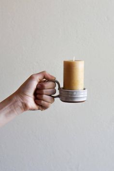 a hand holding a small candle holder with a ring on the bottom and an empty cup in the middle