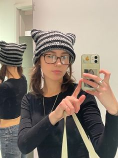 a woman taking a selfie in front of a mirror wearing cat ears and holding a cell phone