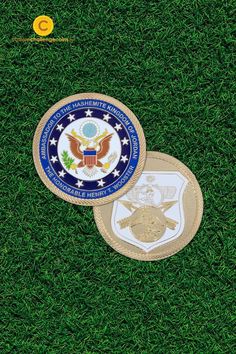 two patches with the seal and emblem on them are laying in the middle of green grass