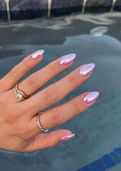 a woman's hand with pink and white manicures on it, next to a pool