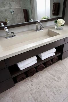 a bathroom vanity with two sinks and towels on the counter top, in front of a large mirror