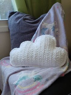 a blanket and pillow on a chair next to a window