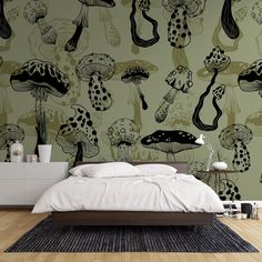 a bed sitting in front of a green wall with black and white mushrooms on it