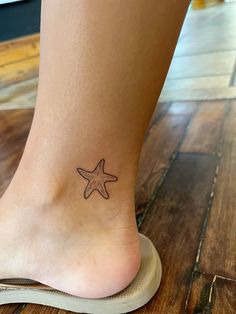 a starfish tattoo on the foot of a woman's right foot, which is sitting on a wooden floor