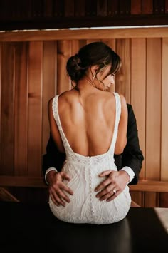 the back of a bride's dress as she sits at a table with her hands on her hips