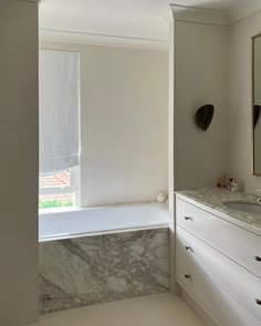 a bathroom with marble counter tops and white cabinets, along with a large mirror on the wall