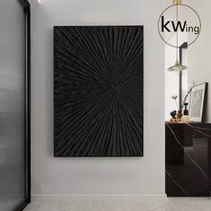 a black wall hanging on the side of a white wall next to a mirror and cabinet