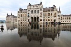 a large building with many windows on the front and side of it, reflecting in water