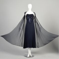 "You'll look like a princess in this elegant 1960s navy blue silk evening gown by Cameo Evening Fashions. This formal dress is sleeveless, has an empire waist, and features a large silk bow on the bodice. Its accompanying translucent, long floating vest makes this gorgeous dress flowy and feminine. Condition: Very Good Condition Details:  Vest: No notable flaws Dress: Lining has a lightened spot at the center front hem, not visible when worn. Size Marked: Unmarked Approximate Size: Small **Please Check Measurements to be Sure! Textile: Unmarked Silk Lining Type: Vest: Unlined, Dress: Fully Lined Closure: Vest: Center Front Hook, Dress: Metal Back Zip, and Hooks Label: Cameo Evening Fashions Era: 1960s Measurements-  Vest: Shoulder to Shoulder: 17\" Chest/Bust: 46\" Waist: 54\" Hips: 68\" L Silk Evening Gown, Formal Evening Gown, Chiffon Evening Dresses, Blue Sheers, Dress Flowy, Dress Navy Blue, Evening Gowns Formal, Navy Blue Dresses, Formal Evening Dresses