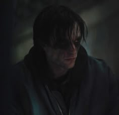 a man with dark hair and glasses looking down at his cell phone in the dark