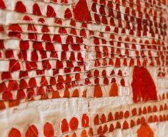 a red and white wall with circles painted on it's side, next to a brick wall