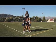 two girls are standing on top of each other in the middle of a football field