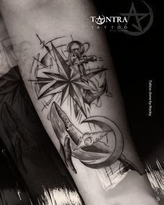 a black and white photo of a tattoo on the arm with an anchor, compass and fish