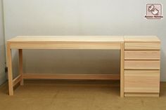 a wooden desk sitting on top of a hard wood floor next to a white wall