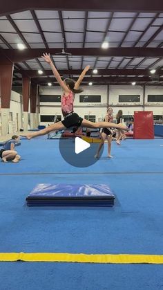 a person jumping on a trampoline in an indoor gym with other people watching