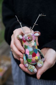 a person holding a small stuffed animal with needles in it's hands while wearing a black sweater