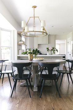 a dining room table with four chairs and a center island in front of the kitchen