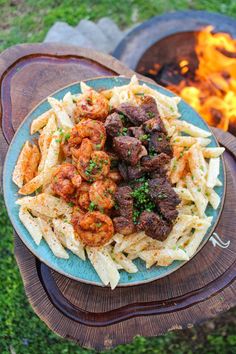 a plate of food sitting on top of a wooden table next to a fire pit