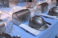 a table topped with lots of silver helmets and glasses on top of blue cloth covered tables