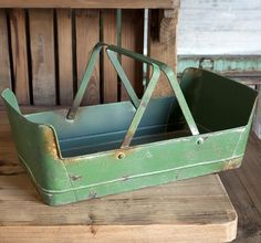 an old green metal container sitting on top of a wooden table