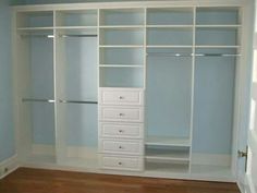 an empty closet with white shelves and drawers