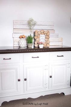 two vases with flowers are sitting on top of a white buffet sideboard that is decorated with wood slices