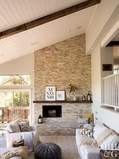 a living room filled with white furniture and a stone fire place in the middle of it