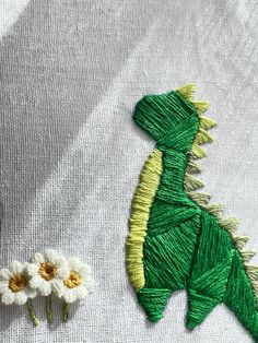 a close up of a piece of cloth with flowers on it and a dragon made out of yarn