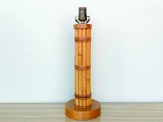 a bamboo lamp is sitting on a wooden base and has a metal light attached to it