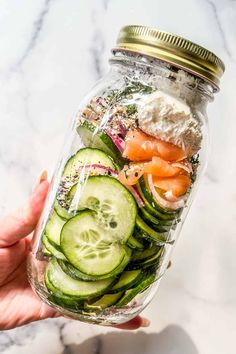 a mason jar filled with cucumber, carrots and other veggies