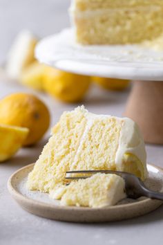 a piece of cake on a plate with a fork in it and lemons behind it