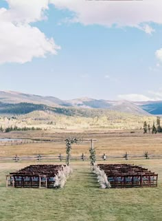 an outdoor ceremony set up in the middle of a field with mountains in the background