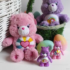 three stuffed animals sitting next to each other in front of a basket with eggs and grass