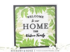 a card with the words welcome to our home and green leaves in black on it