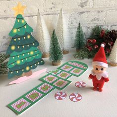 an elf is standing next to some christmas trees and candy canes on the table