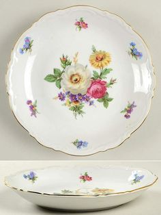 two plates with flowers painted on them, one is white and the other is gold