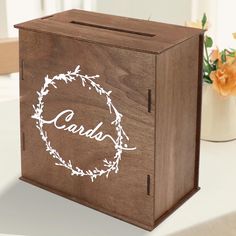 a wooden box sitting on top of a table next to a vase with flowers in it