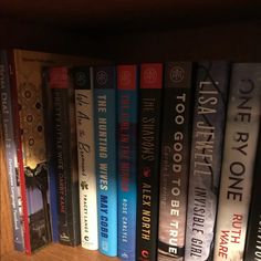 a row of books sitting on top of a wooden book shelf next to each other