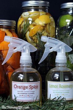 bottles of lemon rosemary and orange spice sit in front of jars filled with fruit