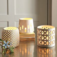 three white candle holders sitting on top of a table