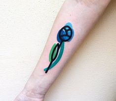 a blue flower tattoo on the left forearm and hand with green leaves painted on it