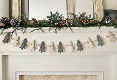 a mantel decorated with pine cones and garland