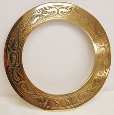 a gold plate with an ornate design on the inside and outside, sitting on a white surface