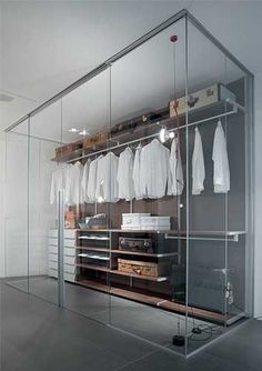 the closet is filled with white shirts and other items in glass cases on shelves,